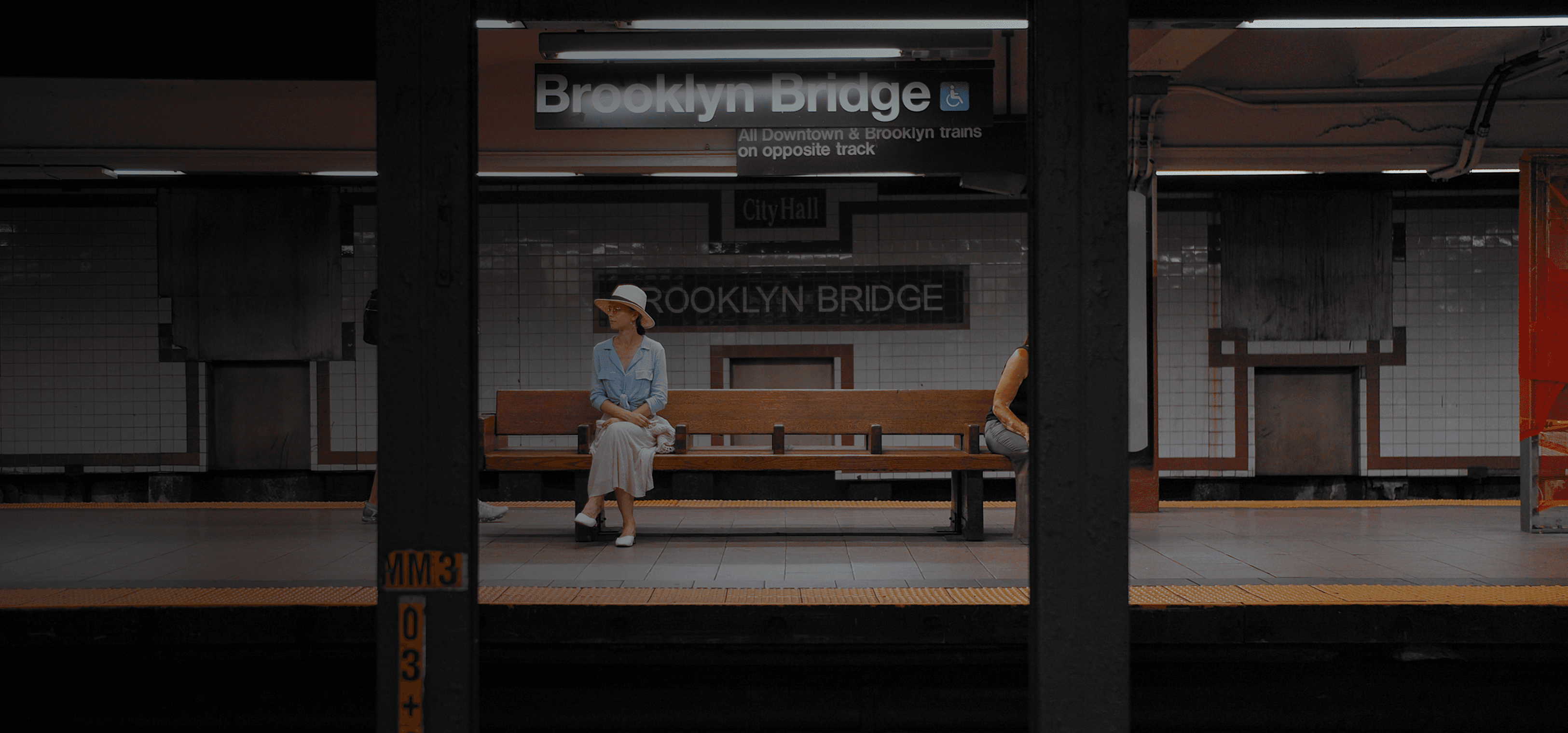 Uma mulher sentada em um banco em uma estação de metrô