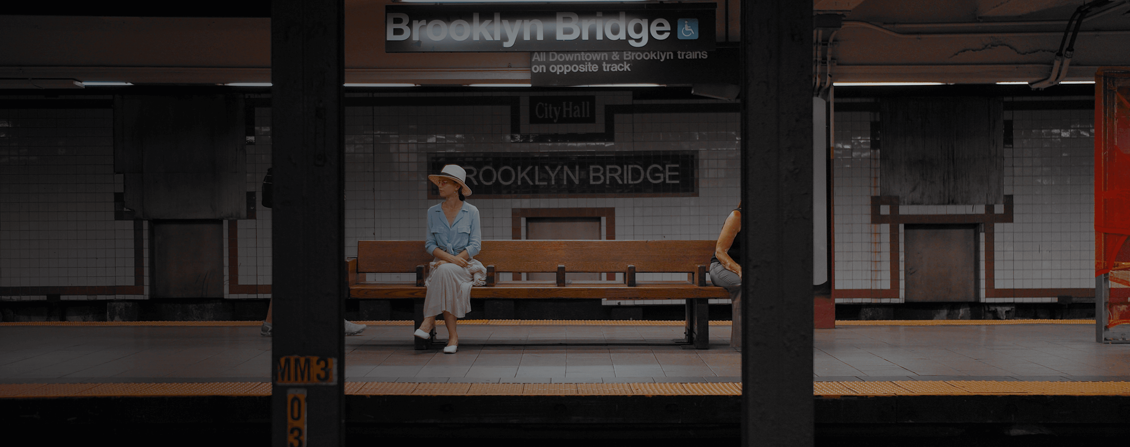 Uma mulher sentada em um banco em uma estação de metrô