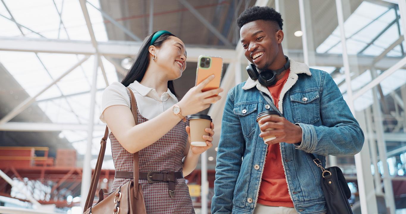 Dois estudantes sorrindo e olhando para um smartphone, representando as soluções de aprendizado de idiomas da Rosetta Stone para escolas, que promovem um aprendizado interativo e acessível pelo celular.